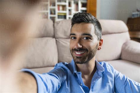 Portrait of smiling young man taking selfie at home stock photo