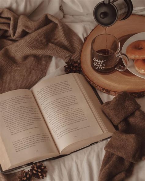 an open book, cup of coffee and donuts on a bed