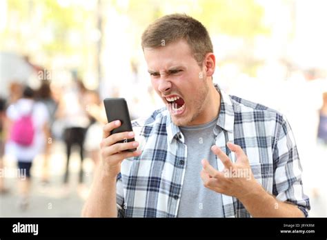 Angry man holding crashed mobile phone on the street Stock Photo - Alamy