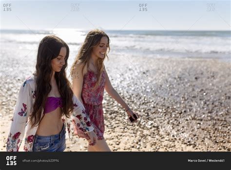 Two best friends walking along the beach stock photo - OFFSET