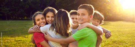 Happy friends hugging in green summer park. Group of children having fun together. Bunch of ...