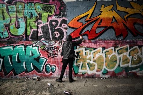 Image of Teenage graffiti artist spray painting a wall - Austockphoto