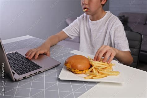 Children bad eating habits, Kid eating unhealthy junk food and playing computer games Stock ...