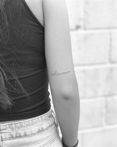 "Eleven" lettering tattoo on the tricep.