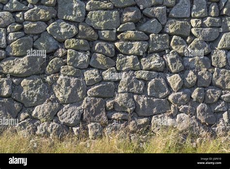 Irregular stonework / roadside granite stone wall with grass verge vegetation Stock Photo - Alamy