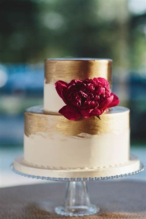 Picture Of metallic gold wedding cake with a burgundy flower