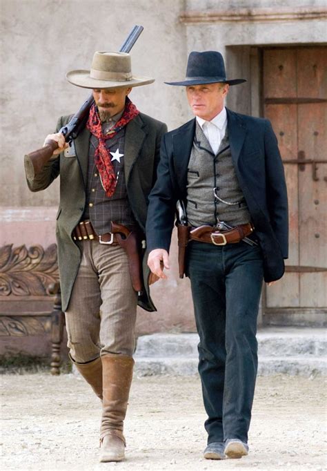 two men dressed in period clothing walking down the street