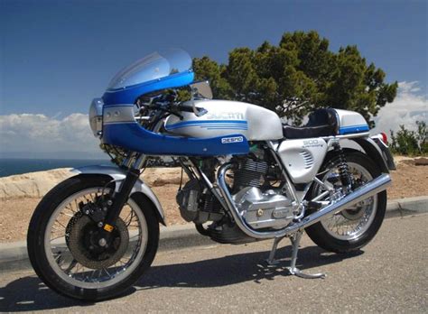 a blue and white motorcycle parked on the side of the road next to the ocean