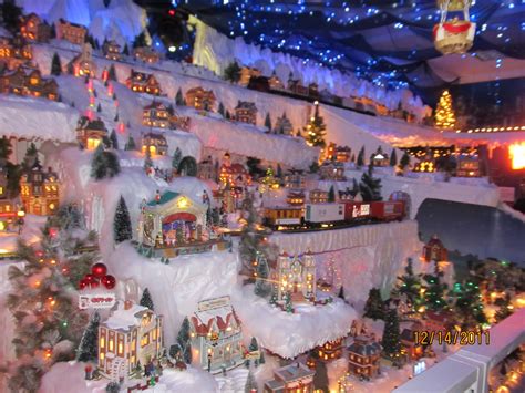 a christmas village is shown with lights and trees on the top of it, along with other holiday ...