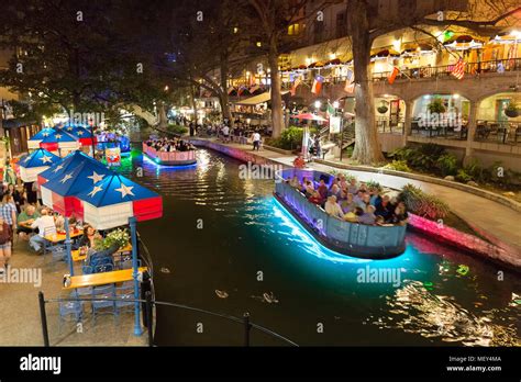 San Antonio Texas river walk at night - a tourist boat on the San Antonio River, the riverwalk ...