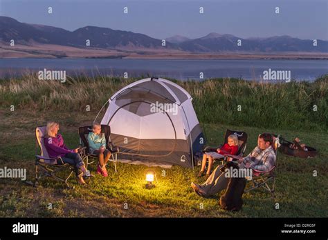 Family sits around the tent while camping at Ennis Lake near Ennis, Montana, USA. (MR Stock ...