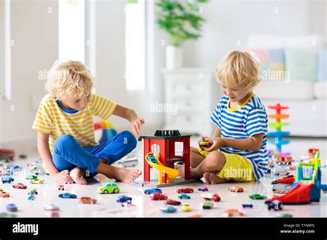 Kids play with toy cars in white room. Little boy playing with car and truck toys. Vehicle and ...