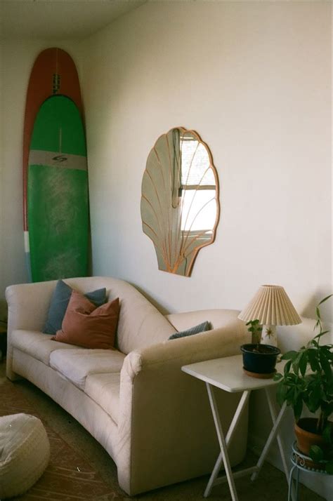 a living room filled with furniture and a green surfboard behind the couch, next to a small table