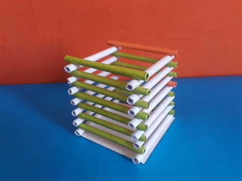 a stack of green and white paper tubes sitting on top of a blue table next to an orange wall