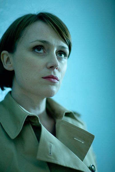 a woman in a trench coat looking off into the distance with an intense look on her face