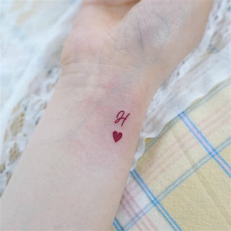 Letter "H" and red heart tattoo located on the wrist.