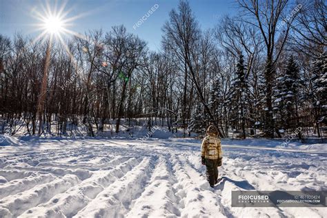 Boy walking through a home made snow maze, USA — woodland, playing - Stock Photo | #461920424