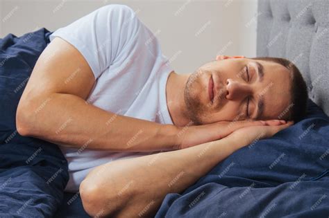 Premium Photo | Top view of a handsome young man sleeping comfortably on the bed at night in his ...