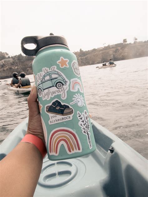 someone is holding up a water bottle with stickers on it while in a kayak