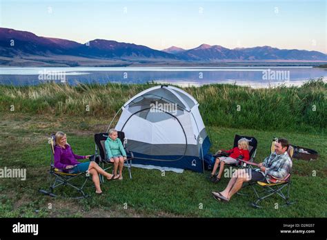 Family sits around the tent while camping at Ennis Lake near Ennis, Montana, USA. (MR Stock ...