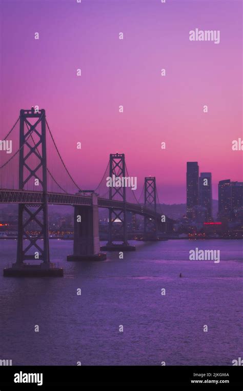 A vertical shot of Golden Gate Bridge against a purple sky during the sunset Stock Photo - Alamy