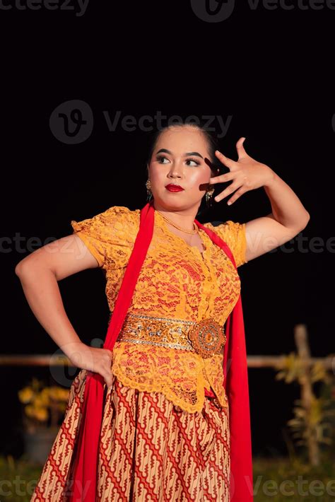 Balinese dancers in yellow color traditional costumes present the dance in front of visitors in ...