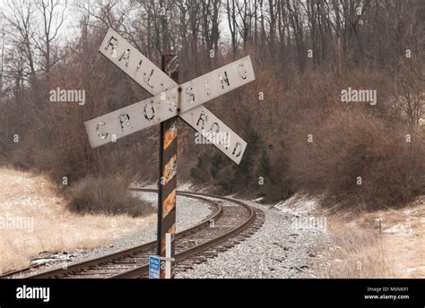 A rail road crossing sign stands along side a curve in RR tracks. Both ...