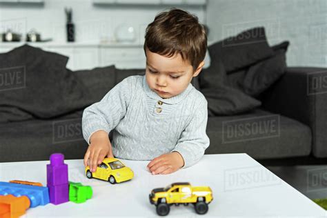 Selective focus of little kid playing with toy cars at table in living room at home - Stock ...