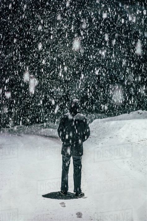 Snow falling over man - Stock Photo - Dissolve