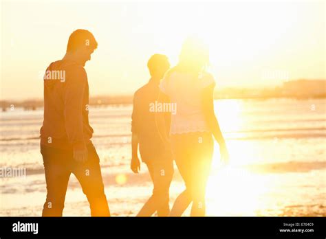 Friends walking on beach at sunset Stock Photo - Alamy