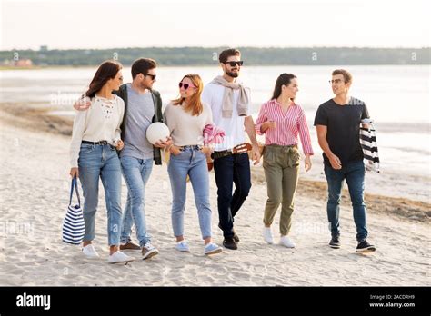 happy friends walking along summer beach Stock Photo - Alamy