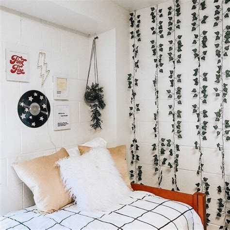 a bedroom with white walls and green plants on the wall behind the headboard, along with a black ...