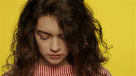 Close up of sad girl face. Offended woman looking to camera on yellow background. Portrait of ...