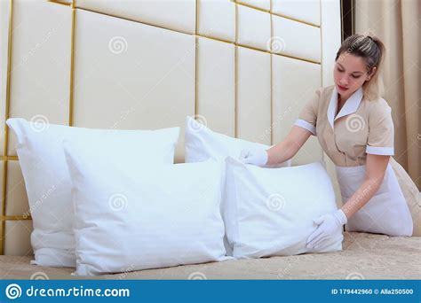 A Maid in an Expensive Hotel Adjusts the Pillows in the Bedroom. Cleaning the Hotel Room. Copy ...