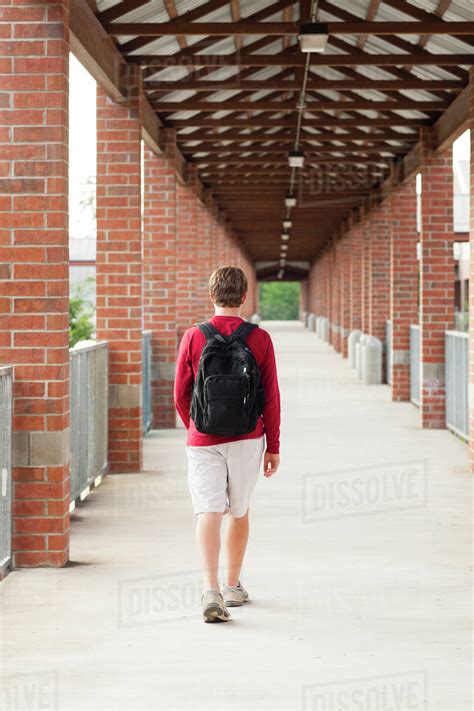 Caucasian teenage boy walking on school campus - Stock Photo - Dissolve