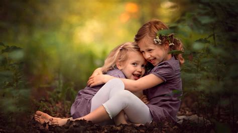 Smiley Cute Sisters Are Hugging Each Other Sitting On Dry Leaves In Blur Green Background 4K HD ...