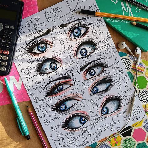 an open notebook with eye drawings on it and a calculator next to it