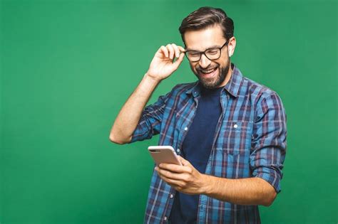 Premium Photo | Smiling young man holding smart phone and looking at it. Portrait of a happy man ...