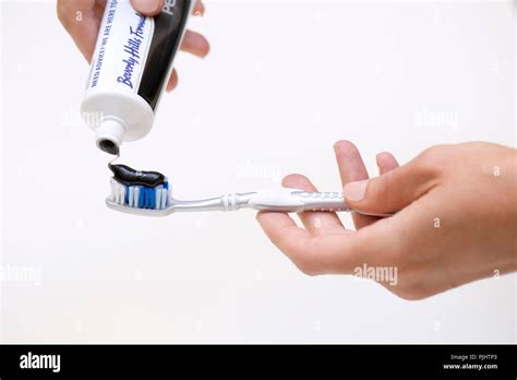 Detail hands putting toothpaste activated charcoal on a toothbrush Stock Photo - Alamy