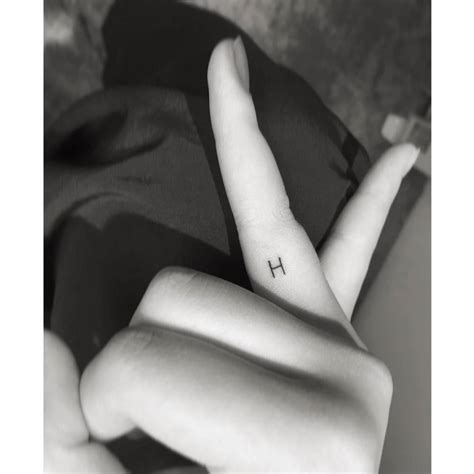 Minimalistic style letter "H" tattoo located on the