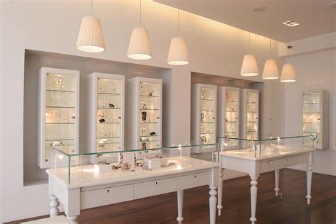 the inside of a jewelry store with glass shelves and lights above them on wooden floors