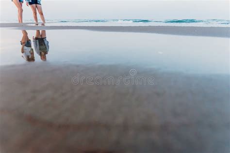 Two Friends Walking at Sunset on a Beach, Reflecting in the Puddles of Sand Stock Image - Image ...