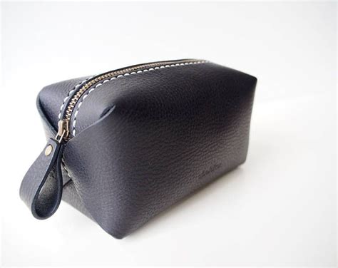 a small black leather pouch with zippers on the inside and outside, sitting on a white surface