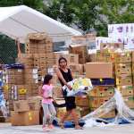 A woman with a child carries a box of food.