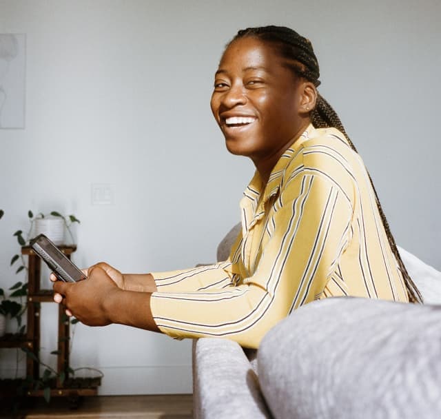 Image of Gina smiling in a couch holding a phone