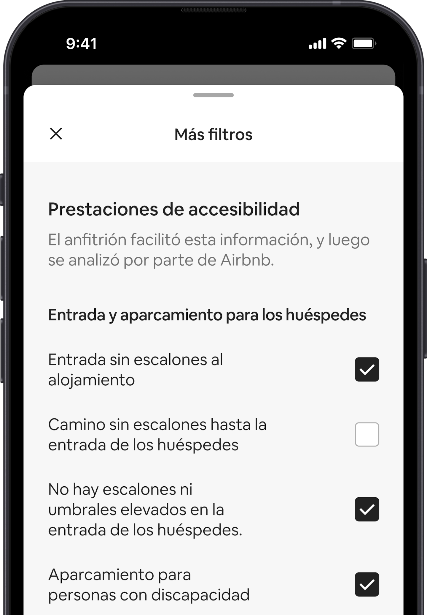 Un teléfono móvil muestra la ventana Más filtros, que es una de las muchas opciones de búsqueda. El encabezado de la sección dice «Prestaciones de accesibilidad». Debajo, las prestaciones de accesibilidad están agrupadas por zonas, como Entrada y aparcamiento para los huéspedes. Hay casillas de verificación para que puedas seleccionar todas las prestaciones que quieras.