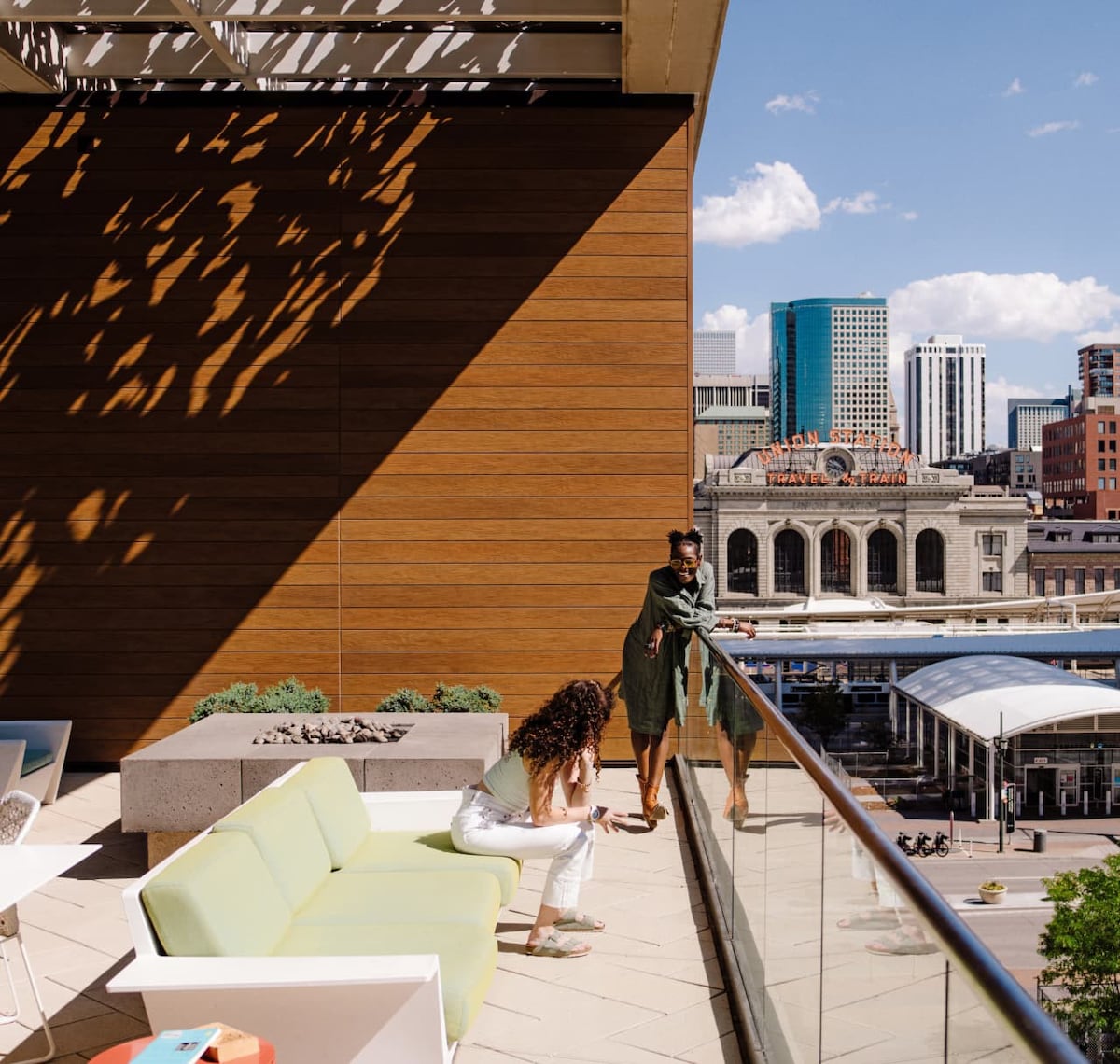 Image of two people on a sunny balcony overlooking a city skyline