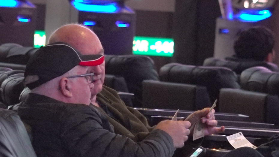 A man handing another man money at the sportsbook