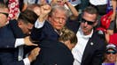 TOPSHOT - Republican candidate Donald Trump is seen with blood on his face surrounded by secret service agents as he is taken off the stage at a campaign event at Butler Farm Show Inc. in Butler, Pennsylvania, July 13, 2024. Donald Trump was hit in the ear in an apparent assassination attempt by a gunman at a campaign rally on Saturday, in a chaotic and shocking incident that will fuel fears of instability ahead of the 2024 US presidential election. The 78-year-old former president was rushed off stage with blood smeared across his face after the shooting in Butler, Pennsylvania, while the gunman and a bystander were killed and two spectators critically injured.