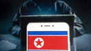 In this photo illustration a democratic People&apos;s Republic of Korea, commonly known as North Korea flag is seen on an Android mobile device with a figure of hacker in the background. 